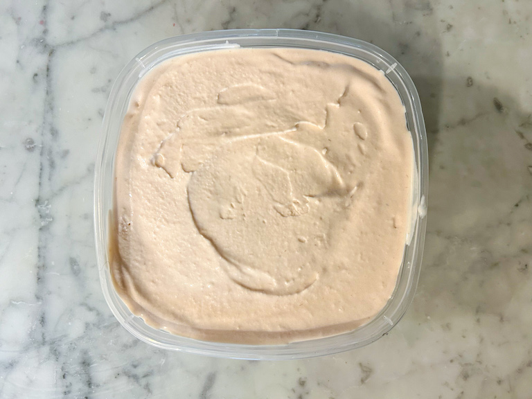 Raspberry white chocolate ice cream in a plastic container