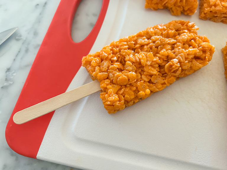 A popsicle shaped rice krispie treat on a cutting board