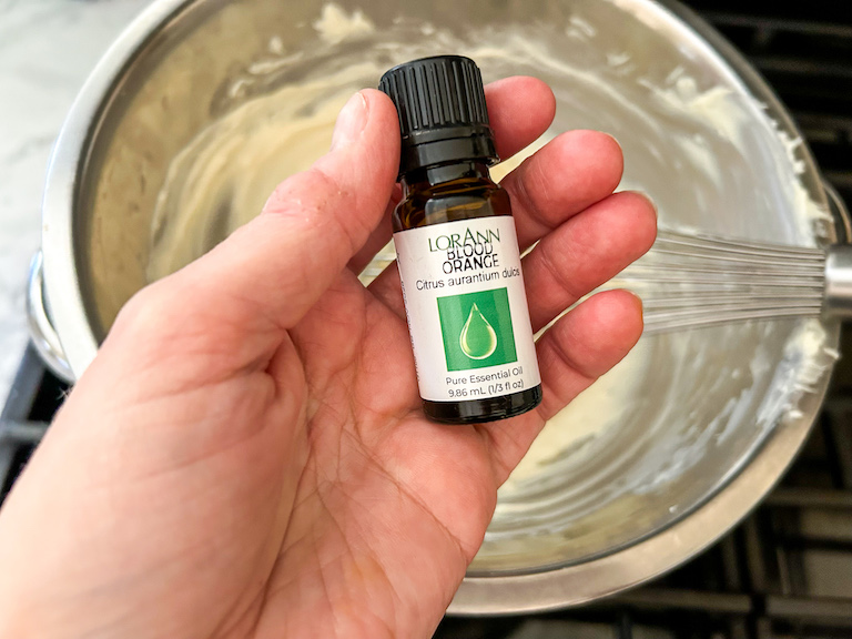 Hand holding a small bottle of orange oil