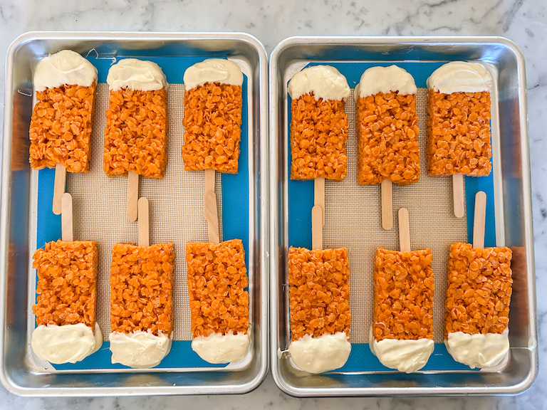 Creamsicle krispie treat popsicles arranged on two small trays
