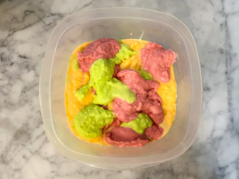 Layered rainbow sherbet in a container before freezing