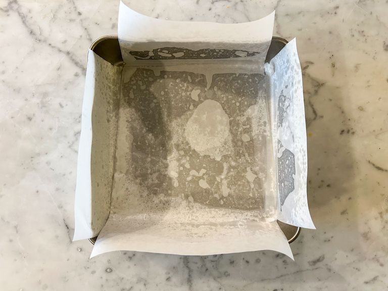 A square parchment lined tin on a marble surface