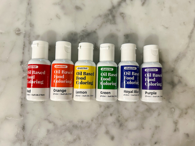 Small bottles of food coloring arranged in a row on a marble surface