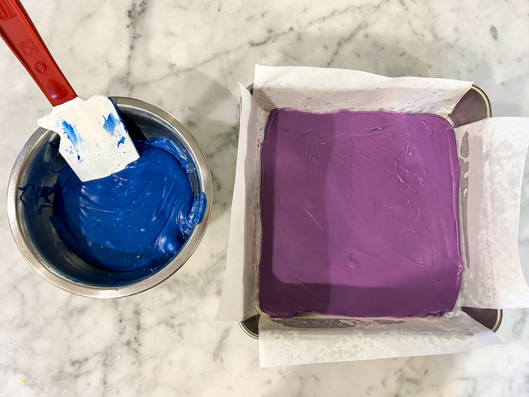 A bowl of blue chocolate next to a pan of purple fudge