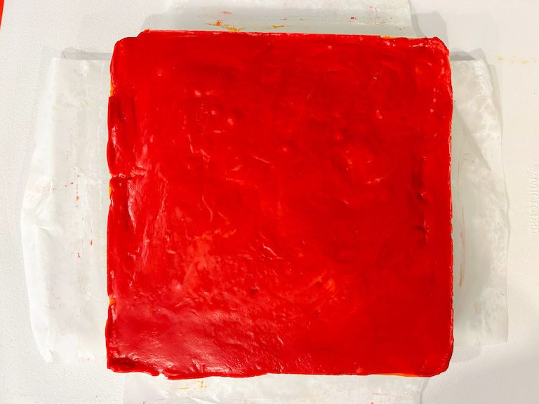 A slab of red fudge on a white cutting board