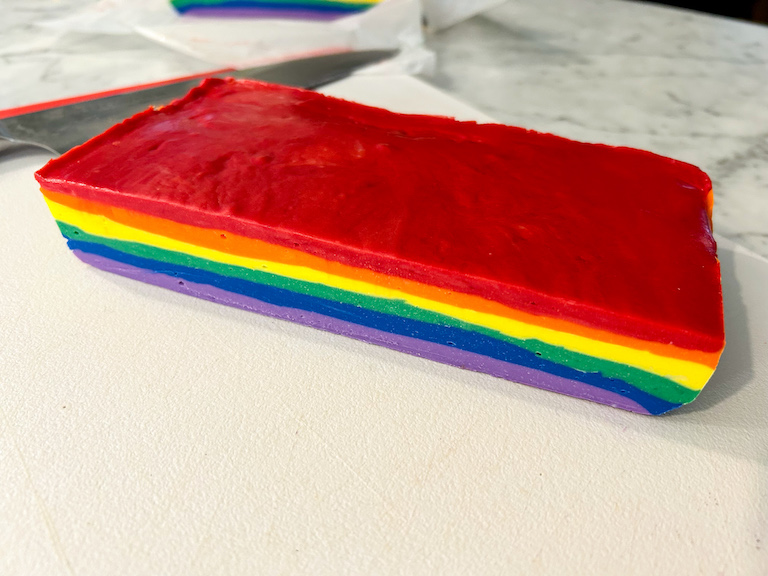 A sliced slab of rainbow fudge on a cutting board