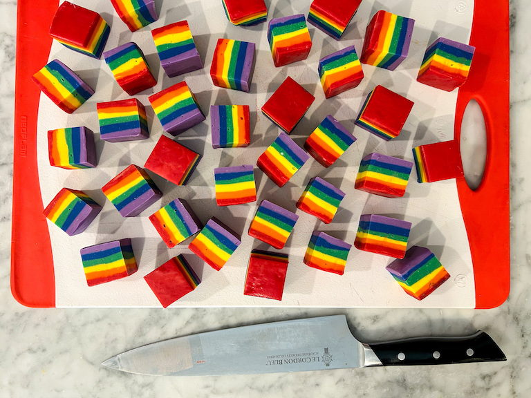 Slices of rainbow fudge on a cutting board with a knife