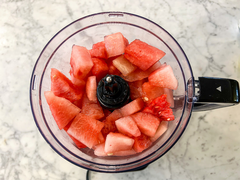 Chunks of fresh watermelon in the bowl of a food processor