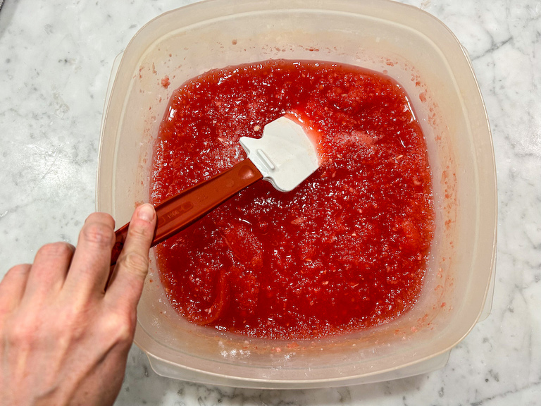 Hand stirring watermelon granita with a spatula