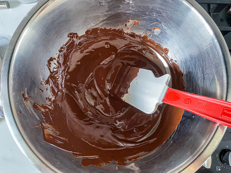 Melted chocolate in a metal bowl with a spatula