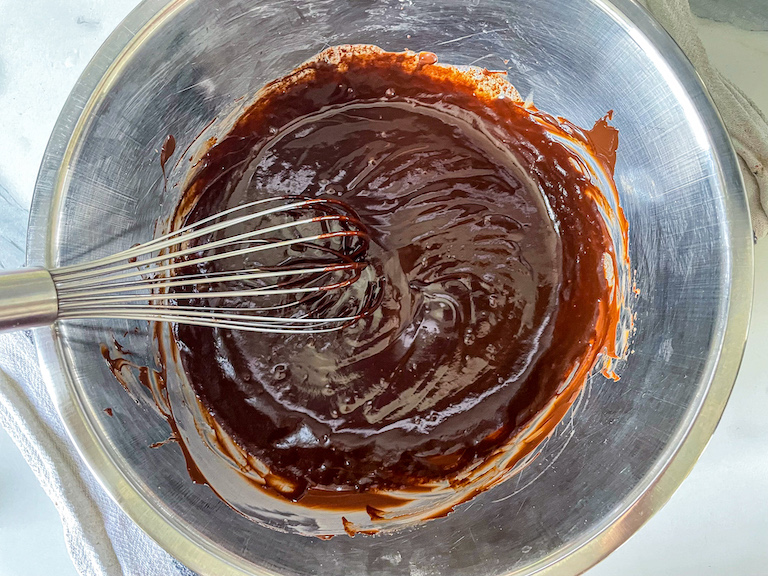 Ganache in a bowl with a metal whisk