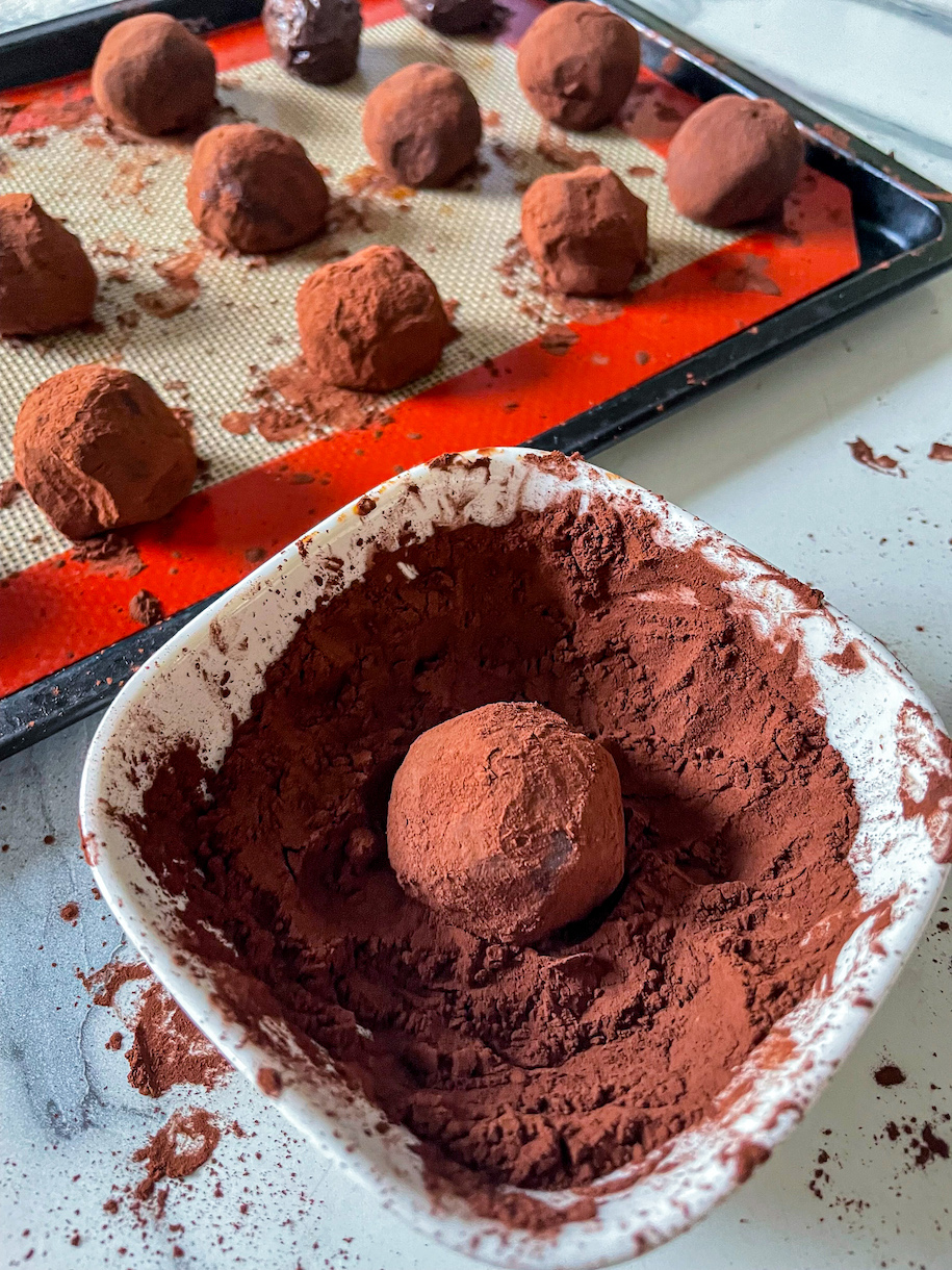 Rolling a truffle in a dish of cocoa powder