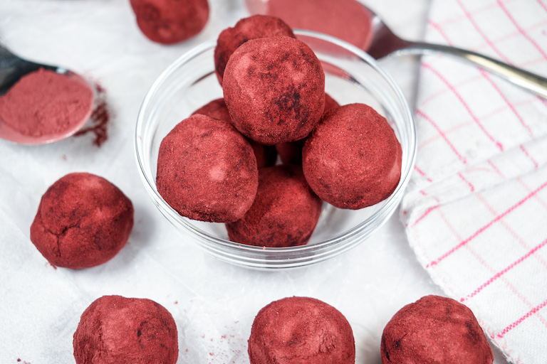 Beet and chocolate truffles in a small bowl, arranged on a white surface