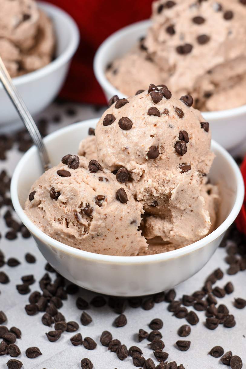 A dish of chocolate chery ice cream surrounded by chocolate chips