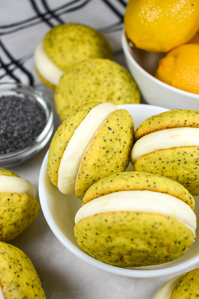A bowl of lemon poppyseed whoopie pies and a dish of lemons