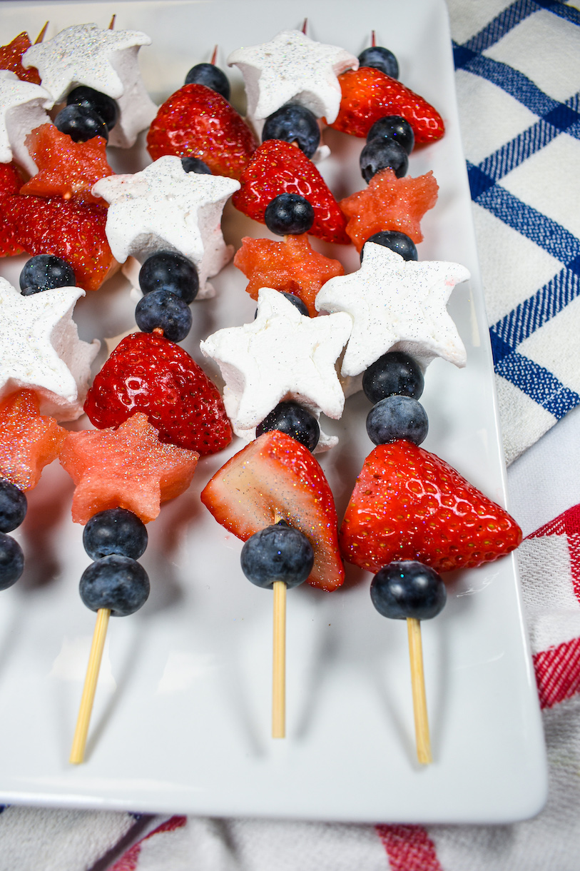 A platter of fruit kebabs made with marshmallows, berries, and watermelon