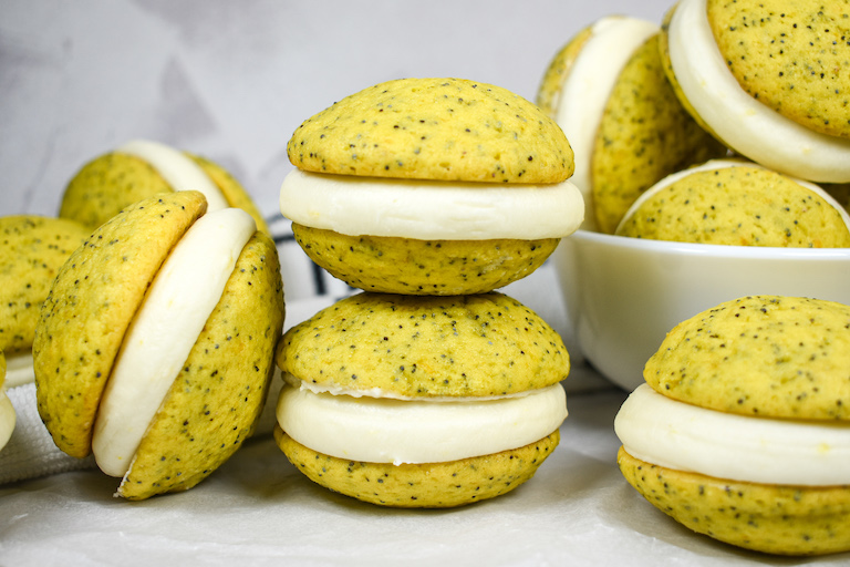 Stacks of lemon poppyseed whoopie pies on a white surface
