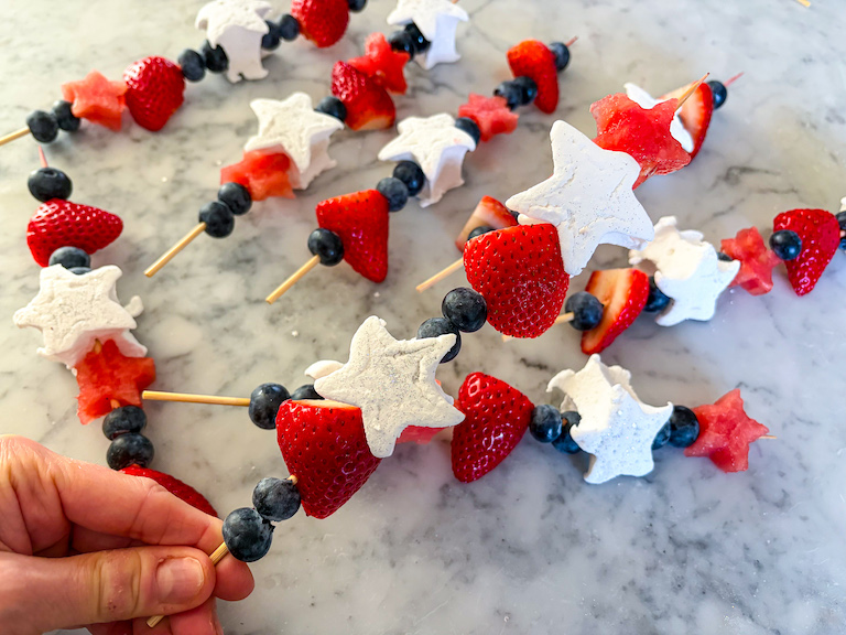 Hand holding a red white and blue fruit skewer