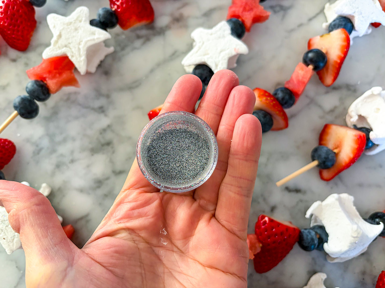 Hand holding a small pot of edible silver glitter