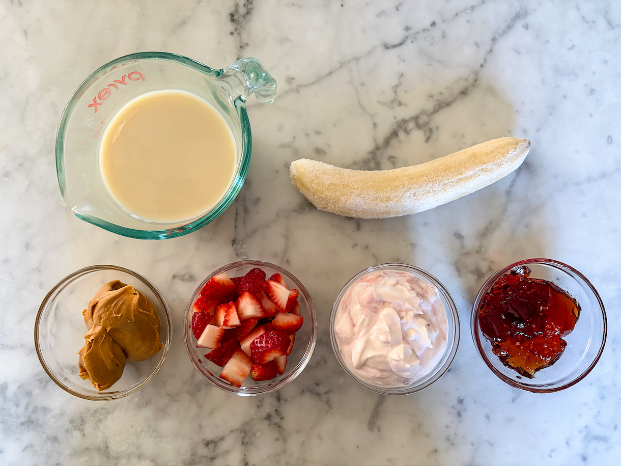 PB&J smoothie ingredients arranged on a marble surface