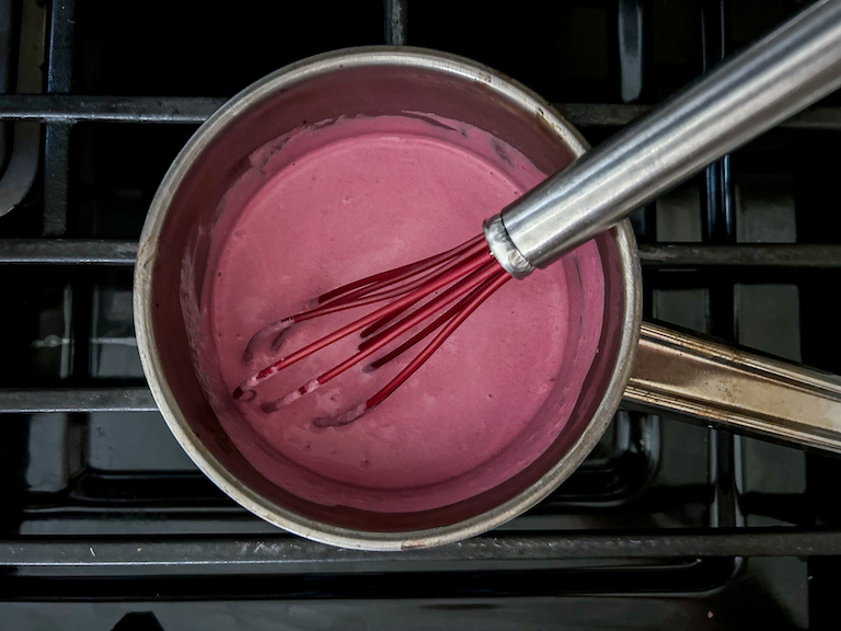 Cream and beet puree in a small saucepan with a whisk