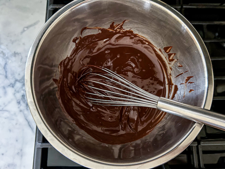 A bowl of melted chocolate with a whisk