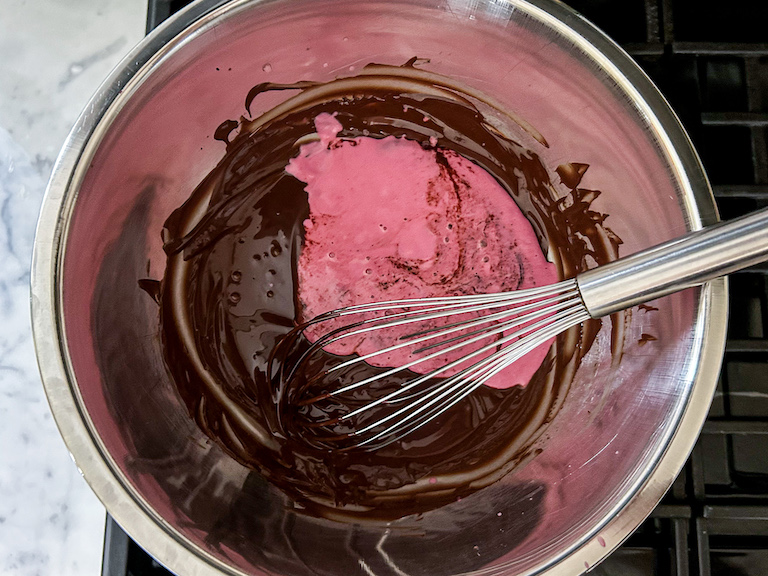 A bowl of chocolate ganache, beet-infused cream, and a whisk