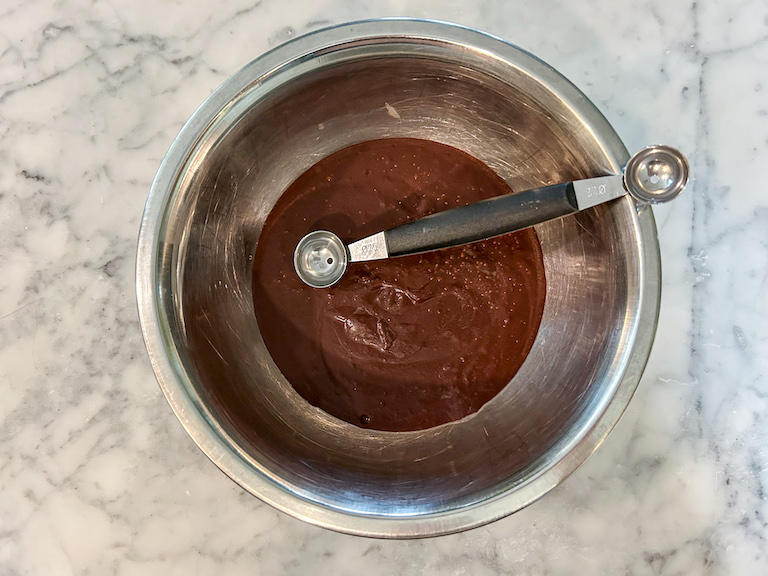 A bowl of chocolate ganache with a melon baller