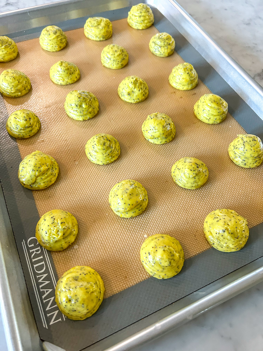 Piped lemon whoopie pie batter on a silicone mat