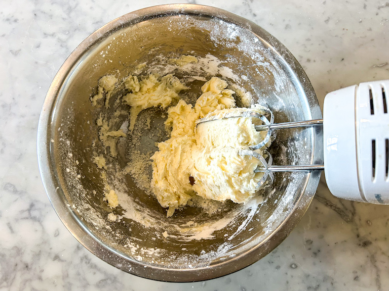 Butter and confectioner's sugar in a bowl with a hand mixer