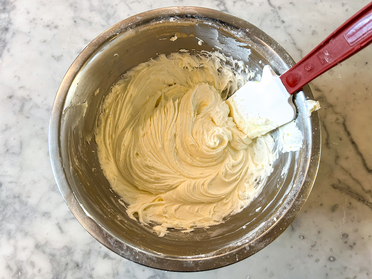 Lemon buttercream in a metal bowl with a spatula