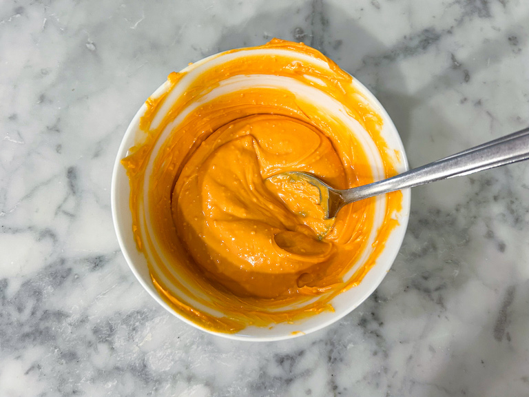 Dish of melted orange chocolate with a spoon