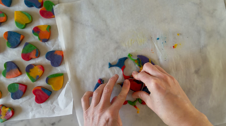 Hands cutting heart shapes with a metal cutter