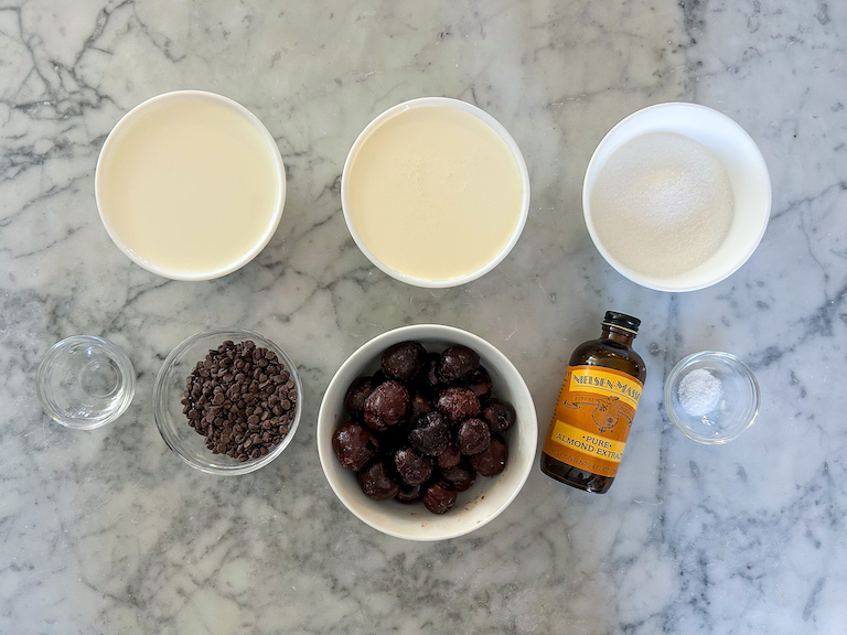 Chocolate and cherry ice cream recipe ingredients arranged on a marble surface