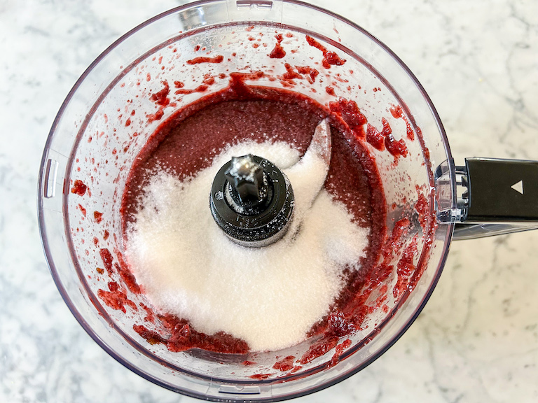 Adding granulated sugar to a food processor of cherry puree