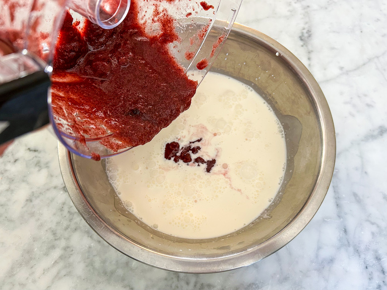 Adding pureed cherries to a bowl of milk and cream