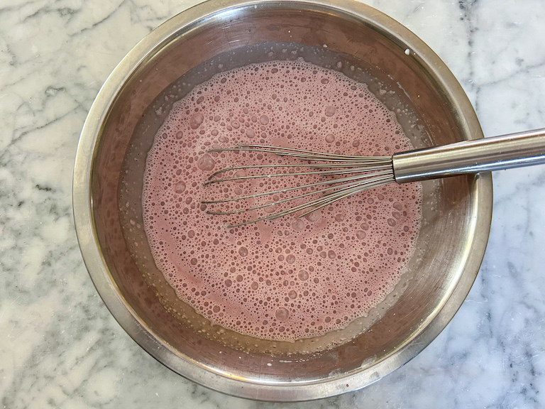 Cherry ice cream base in a bowl with a whisk