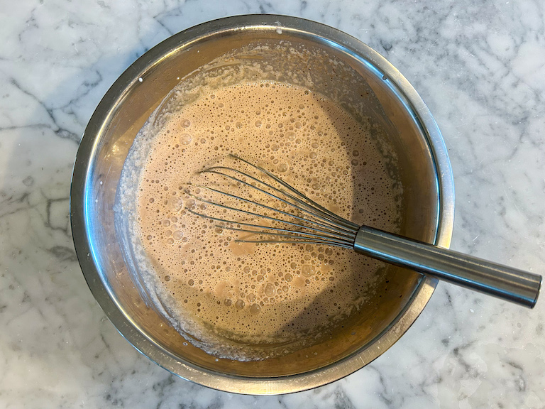 Cherry ice cream base in a metal bowl with a whisk