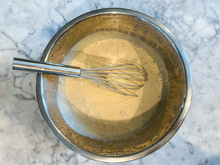 Ice cream base in a metal bowl with a whisk