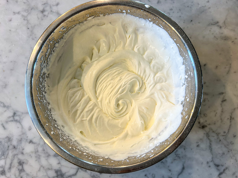 a bowl of whipped cream on a marble surface