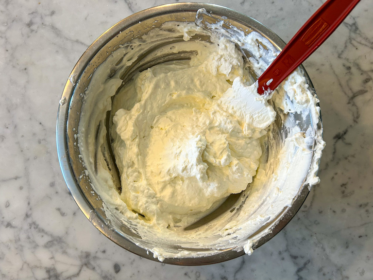 Cheesecake filling in a bowl with a rubber spatula