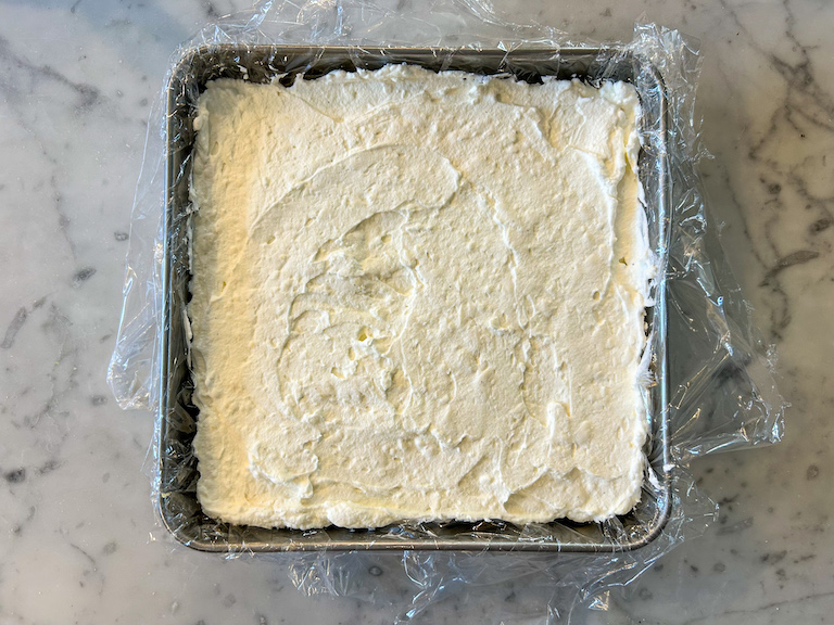 Cheesecake filling spread in a square metal tin