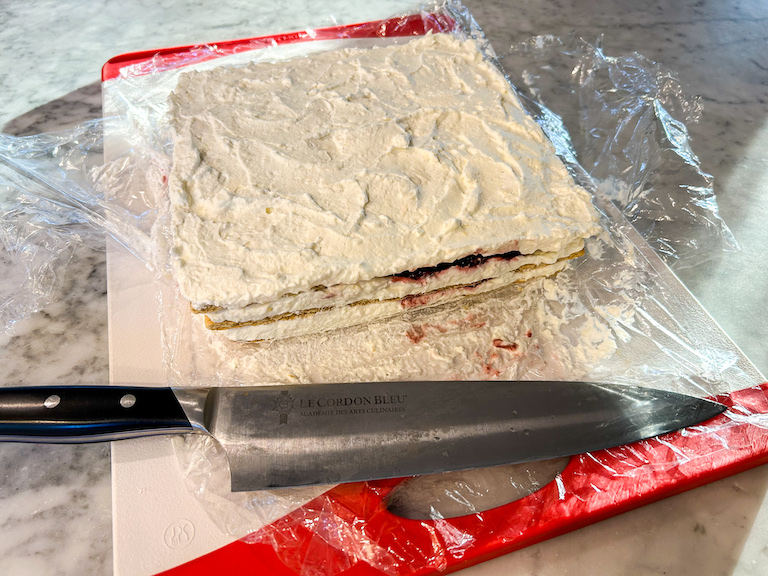 Cherry cheesecake icebox cake on a cutting board with a knife