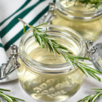 a jar of rosemary syrup with a sprig of rosemary on top