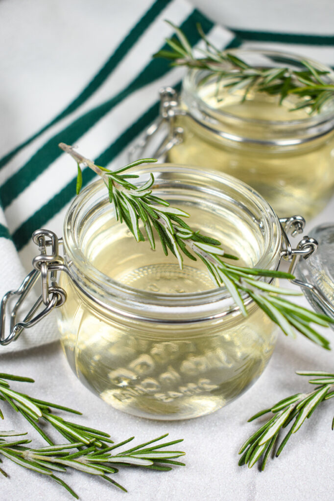 a jar of rosemary syrup with a sprig of rosemary on top