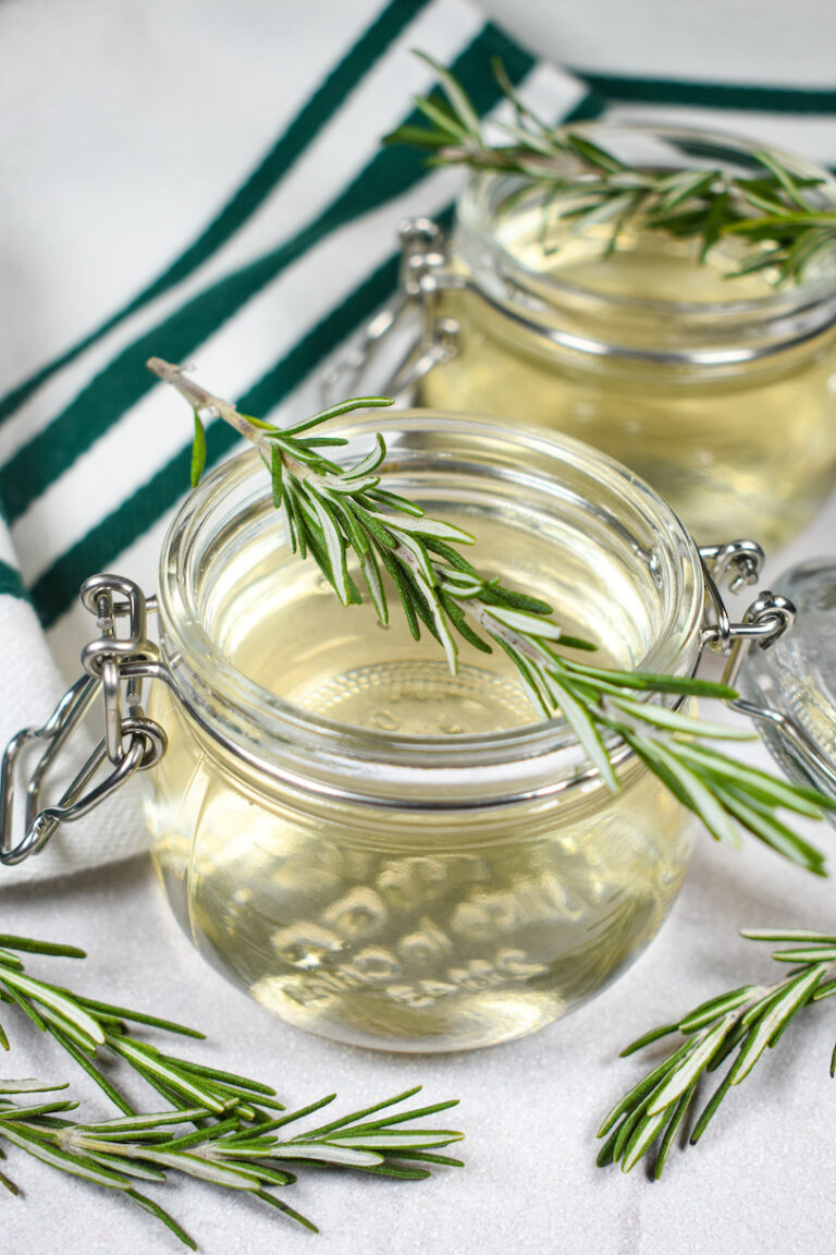 a jar of rosemary syrup with a sprig of rosemary on top
