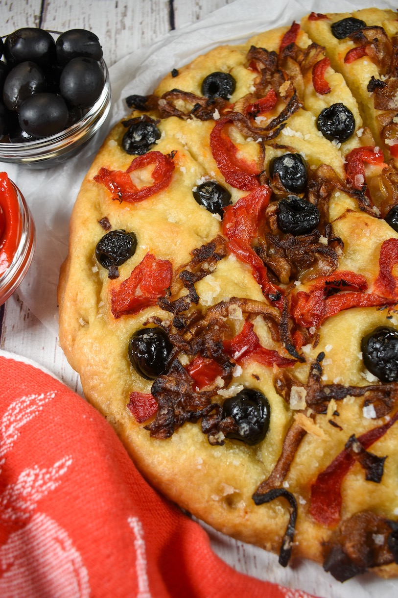Horizontal shot of a round loaf of caramelized onion and roasted red pepper focaccia bread