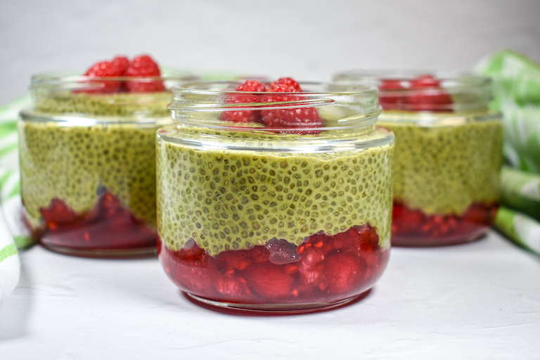 Three jars of raspberry matcha chia seed pudding arranged on a white surface