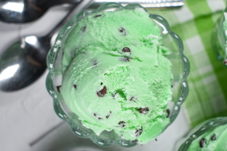 Looking down at scoops of mint chocolate chip ice cream in a glass dish