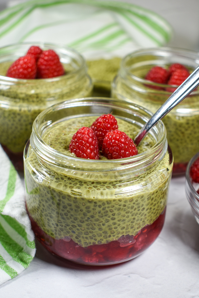 A jar of raspberry matcha chia seed pudding with a spoon